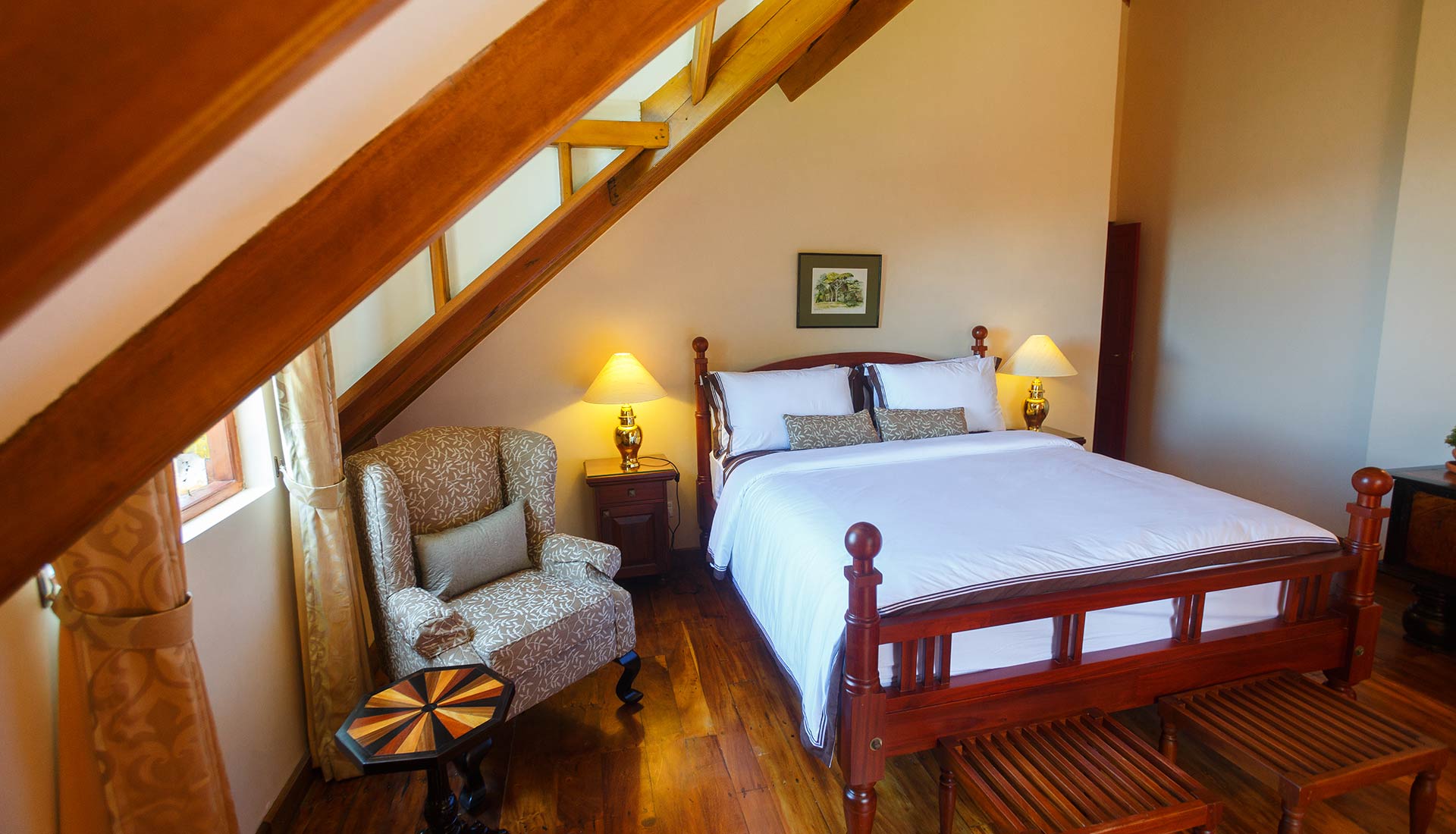 The Double Room with a timber bed, an armchair and a sloping ceiling