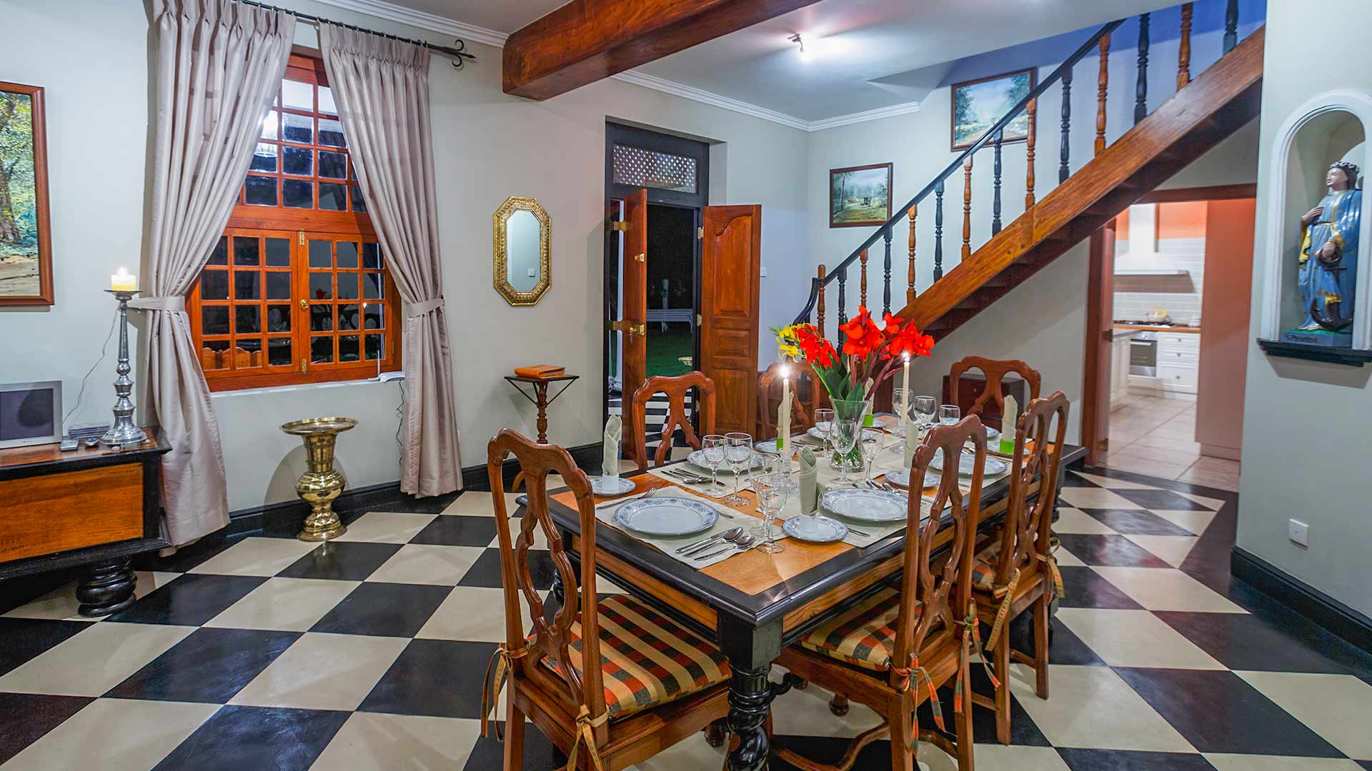 The dining table on a black and white chequered floor, with the timber staircase behind
